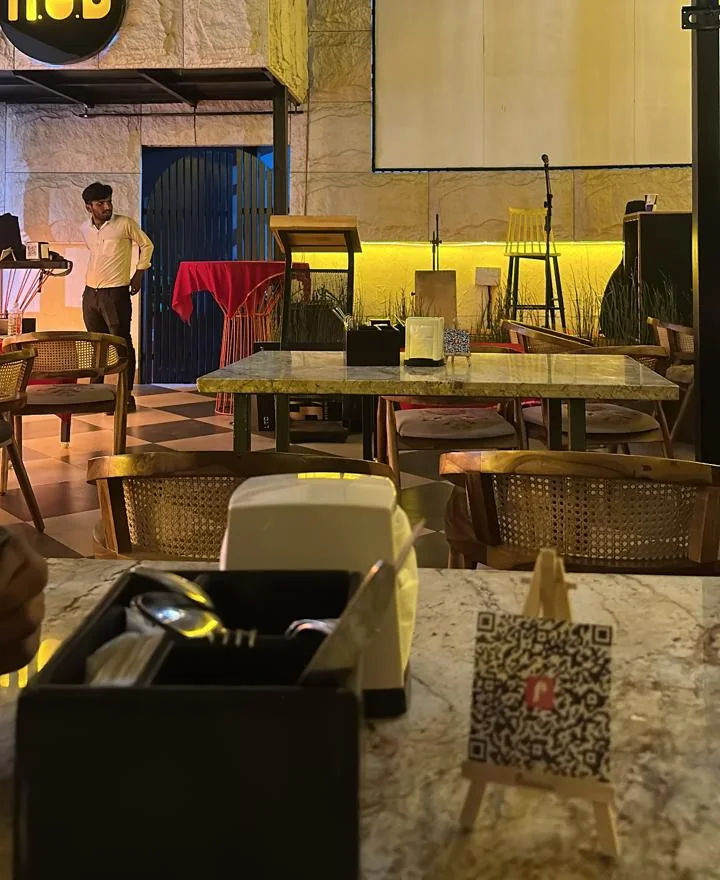 A Prophilehouse QR code standing on a marble table at H.O.D venue, with the stage in the background